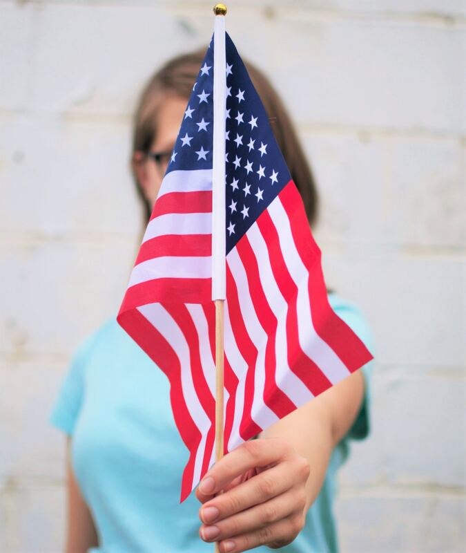 Girl proudly holding American Flag; photo by Fischer Twins on Unsplash.com